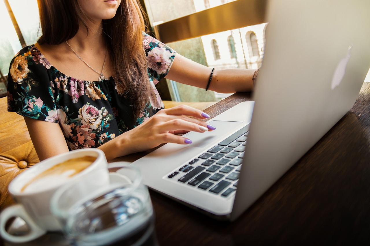 Girl working on her computer while drinking coffee
